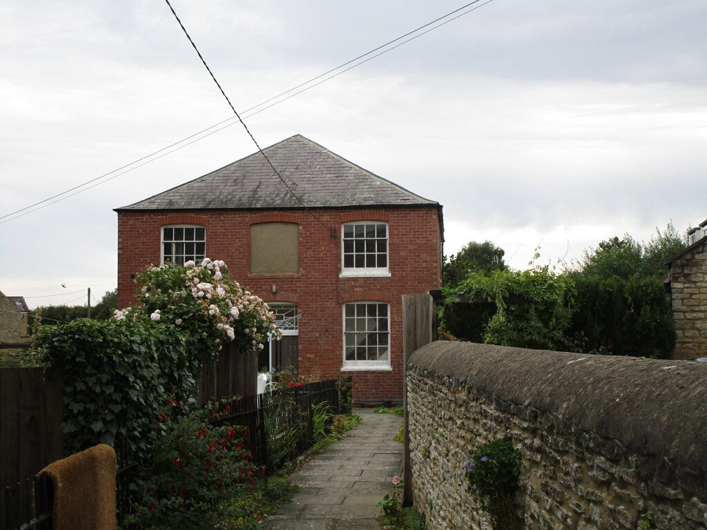 Aldwincle Baptist Church: a plain Georgian red-brick chapel of c. 1823 with sash windows and slate hipped roof, set behind a flagstone path with climbing roses on the front fence